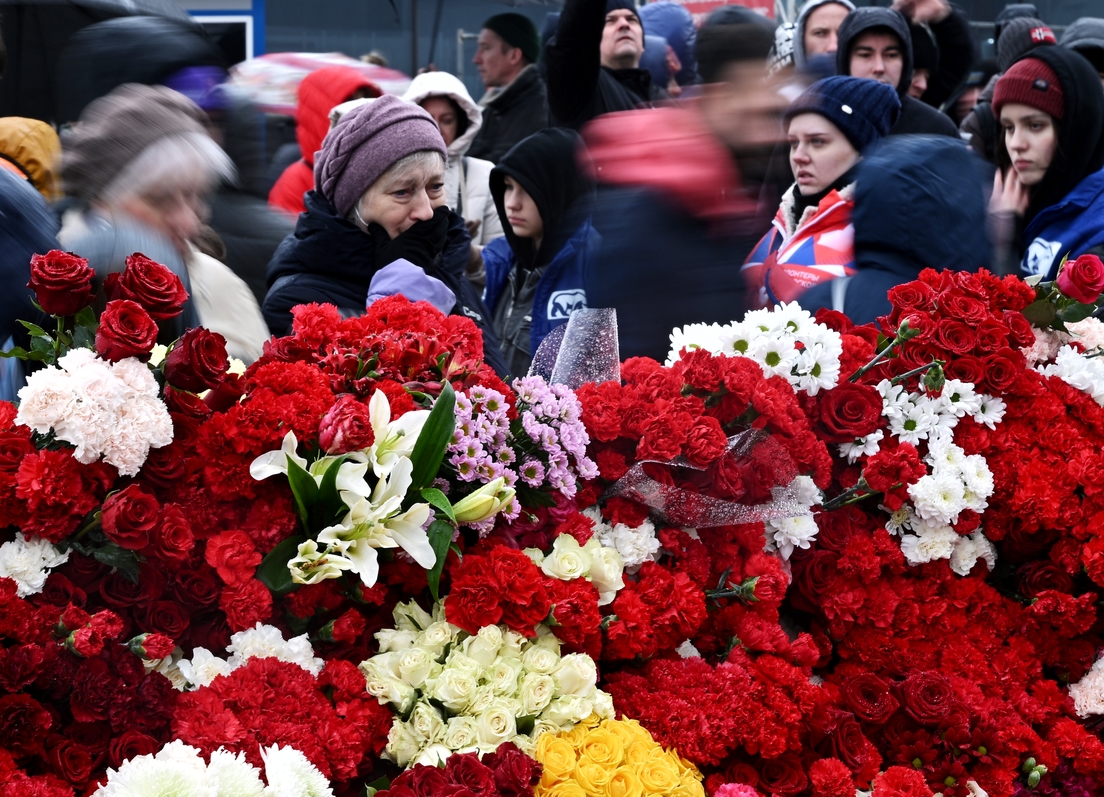 Enormes colas de gente llevando flores al edificio del Crocus City Hall